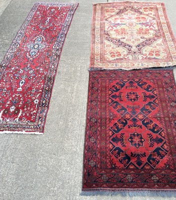 Lot 67 - A Pakistan red ground rug with twin central...