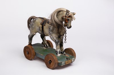 Lot 550 - A child's toy horse on wheels, label to front...