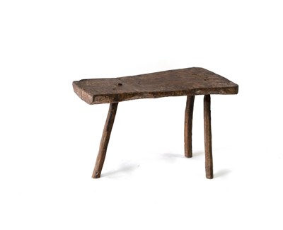 Lot 659 - A primitive three-legged stool, 66cm long