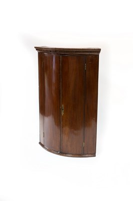 Lot 712 - A George III bowfront corner cupboard with...