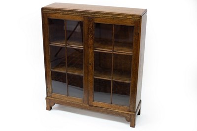 Lot 784 - An oak bookcase enclosed by glazed panel doors,...