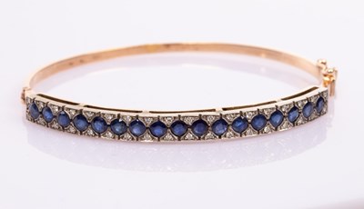 Lot 12 - A sapphire and diamond hinged bangle, set in...