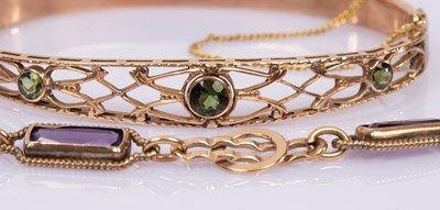 Lot 61 - A hinged bangle set with three peridot in a...