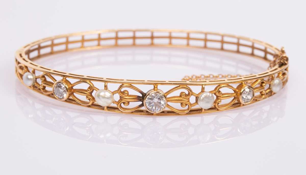 Lot 62 - A 14k yellow gold hinged bangle set with three...