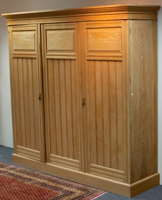 Lot 558 - An Arts & Crafts bleached pine triple wardrobe,...