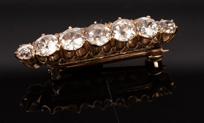 Lot 418 - A diamond seven-stone brooch, the line of...