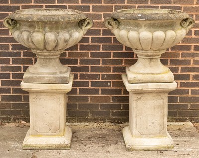 Lot 784 - A pair of composition stone urns of lobed form...