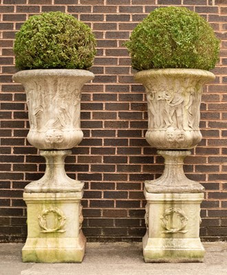 Lot 785 - A pair of composition stone urns the sides...