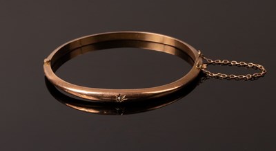 Lot 219 - A 9ct rose gold hinged bangle, gypsy set with...