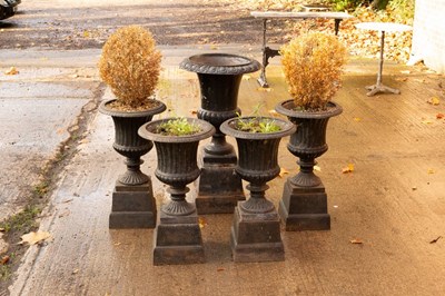 Lot 602 - Four cast iron campana-shaped vases of fluted...