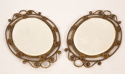 Lot 711 - A pair of brass oval mirrors, the frame...