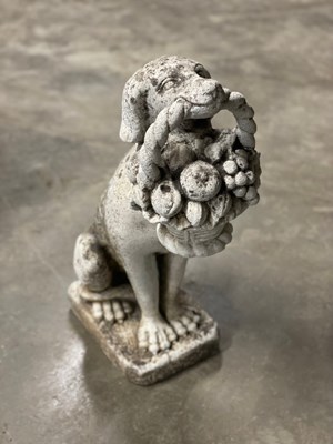 Lot 602 - A reconstituted stone figure of a dog holding...