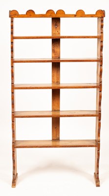 Lot 569 - A Continental pine bookcase, the shaped top...