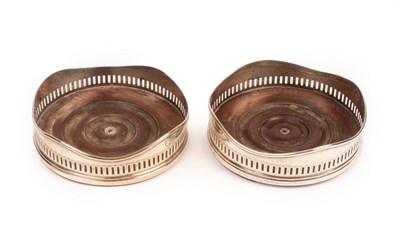 Lot 129 - A pair of George III silver wine coasters,...