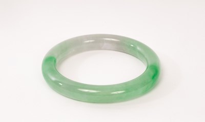 Lot 703 - A green jadeite bangle, 20th Century, 7.5cm...