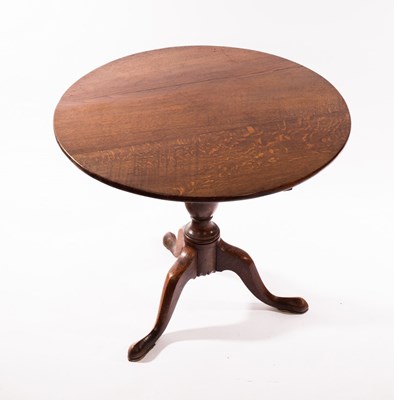 Lot 1130 - A circular oak tilt-top table, on a turned...