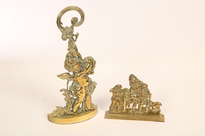 Lot 1359 - Two brass doorstops, the larger a cherub with...