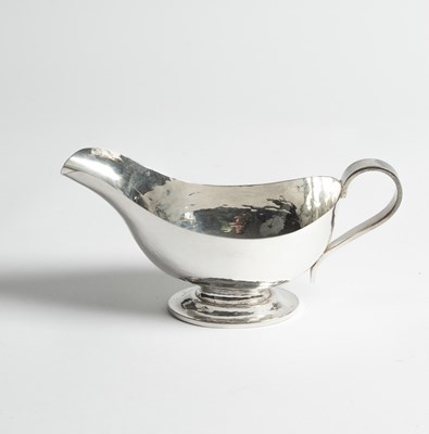 Lot 75 - An Arts & Crafts hammered silver sauce boat