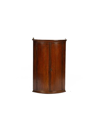 Lot 405 - A George III oak bowfronted corner cupboard