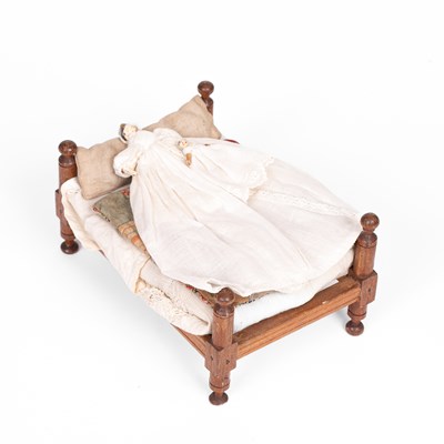 Lot 603 - A larger scale English wooden dolls' house bedstead and two Grodnertal babies