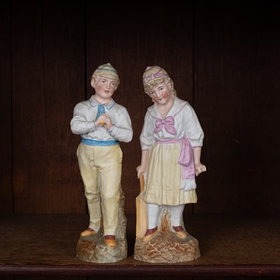 Lot 174 - A pair of Continental biscuit porcelain figures of a gentleman bowler and lady cricketer