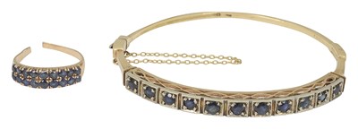 Lot 634 - A yellow metal sapphire hinged bangle